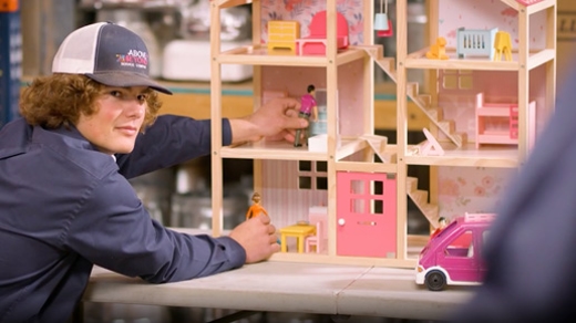 A technician playing with dolls and a dollhouse.